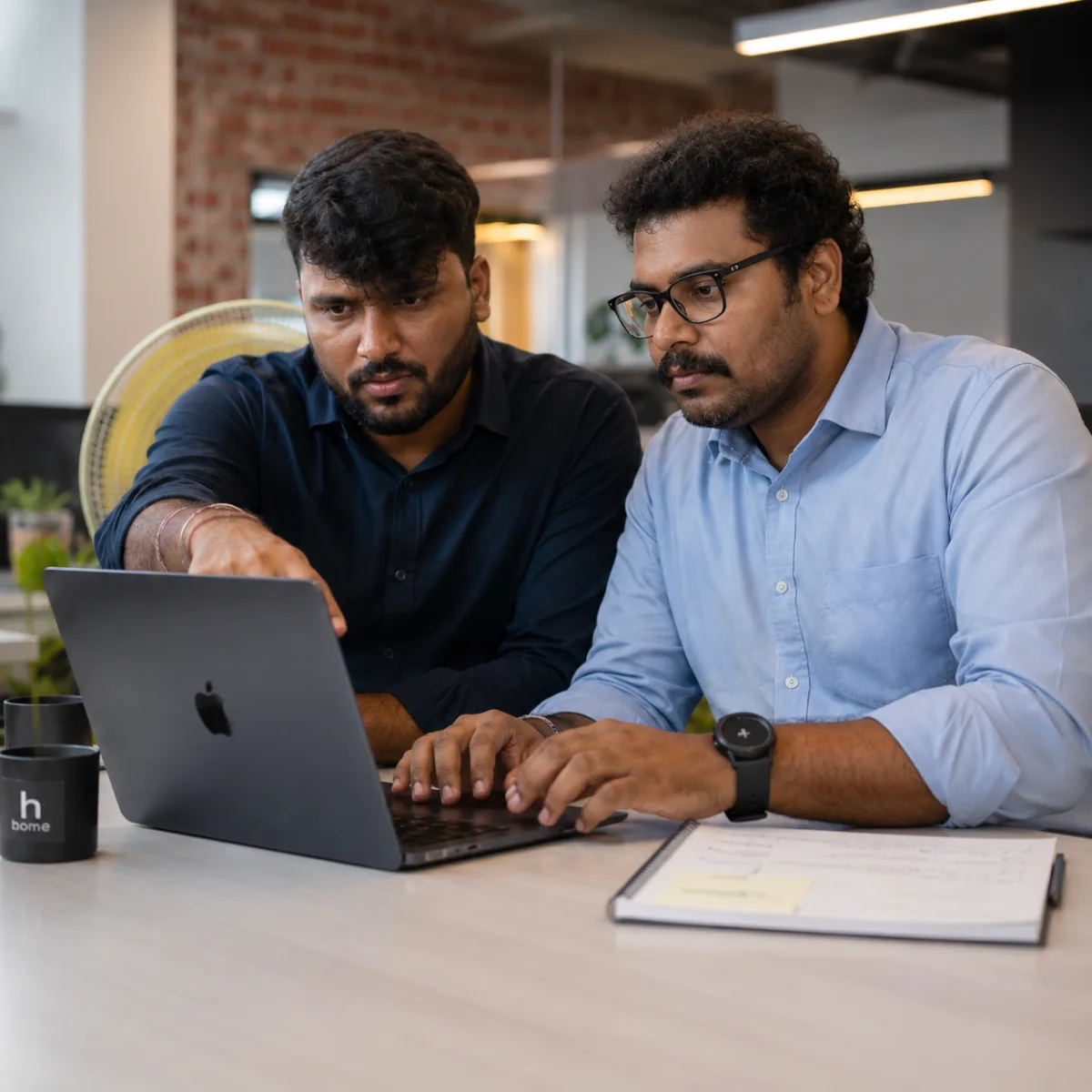 Two Zethic engineers pair-programming at a laptop in the Bengaluru office