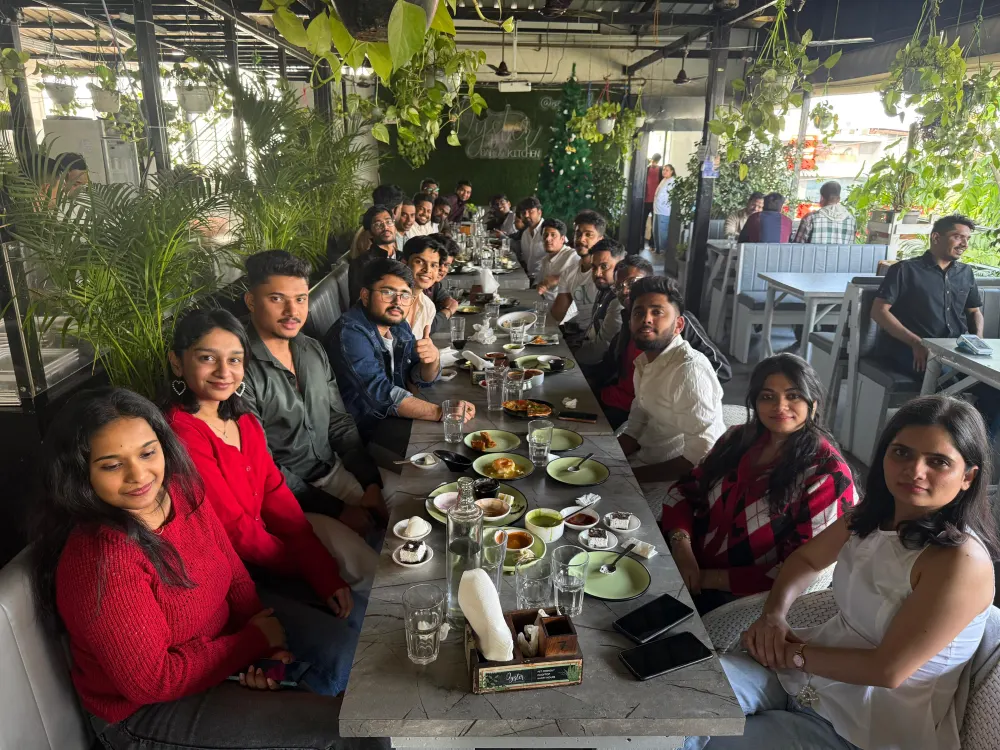 Zethic team seated along a long lunch table at a garden restaurant
